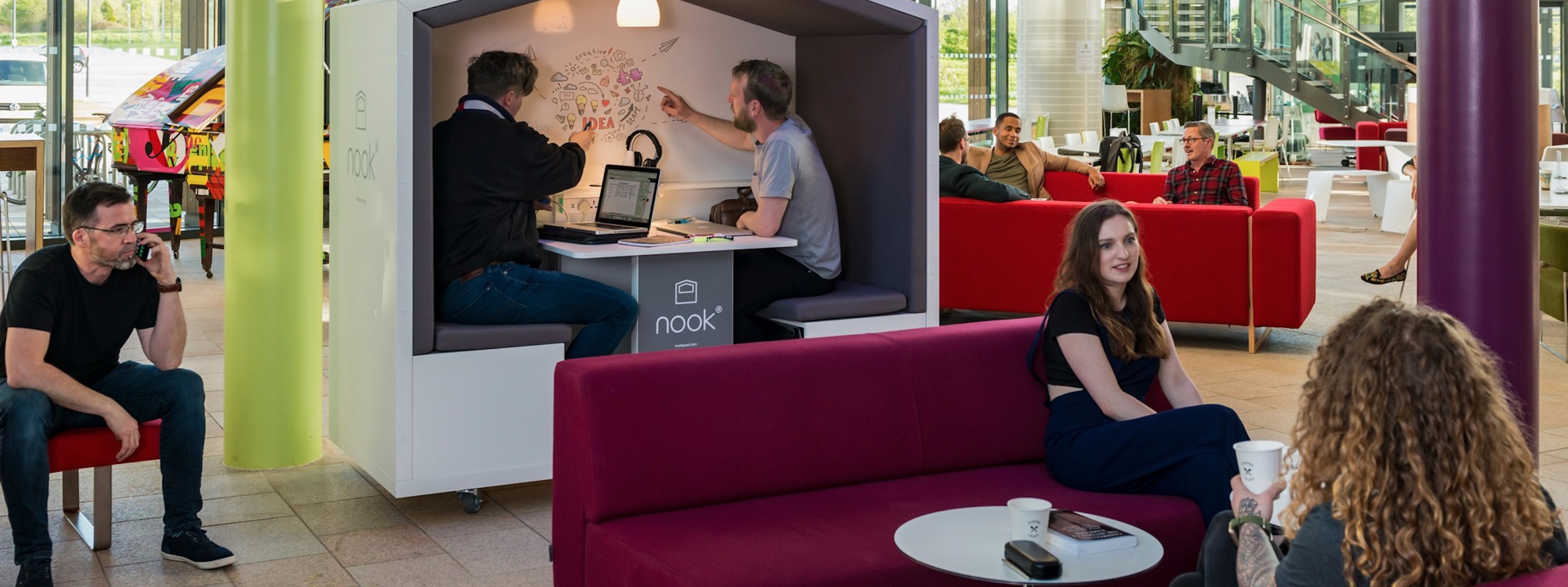 Nook in open office setting with two men inside using a whiteboard
