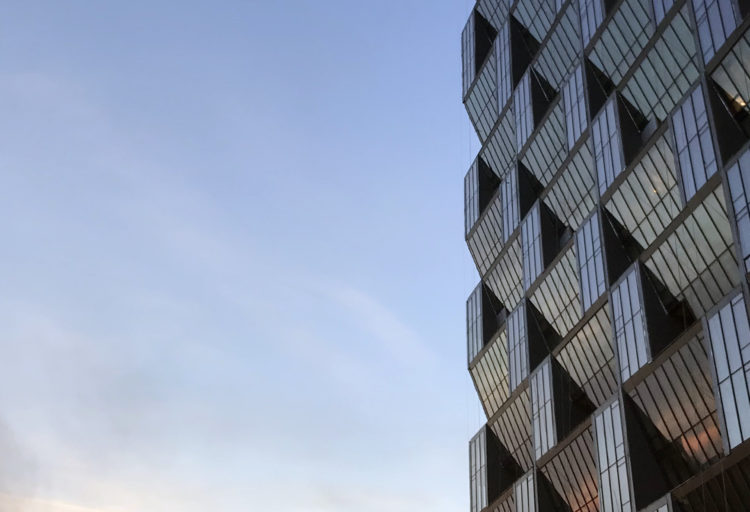 sky view showing exterior facade of glass tower with angled windows for solar carving