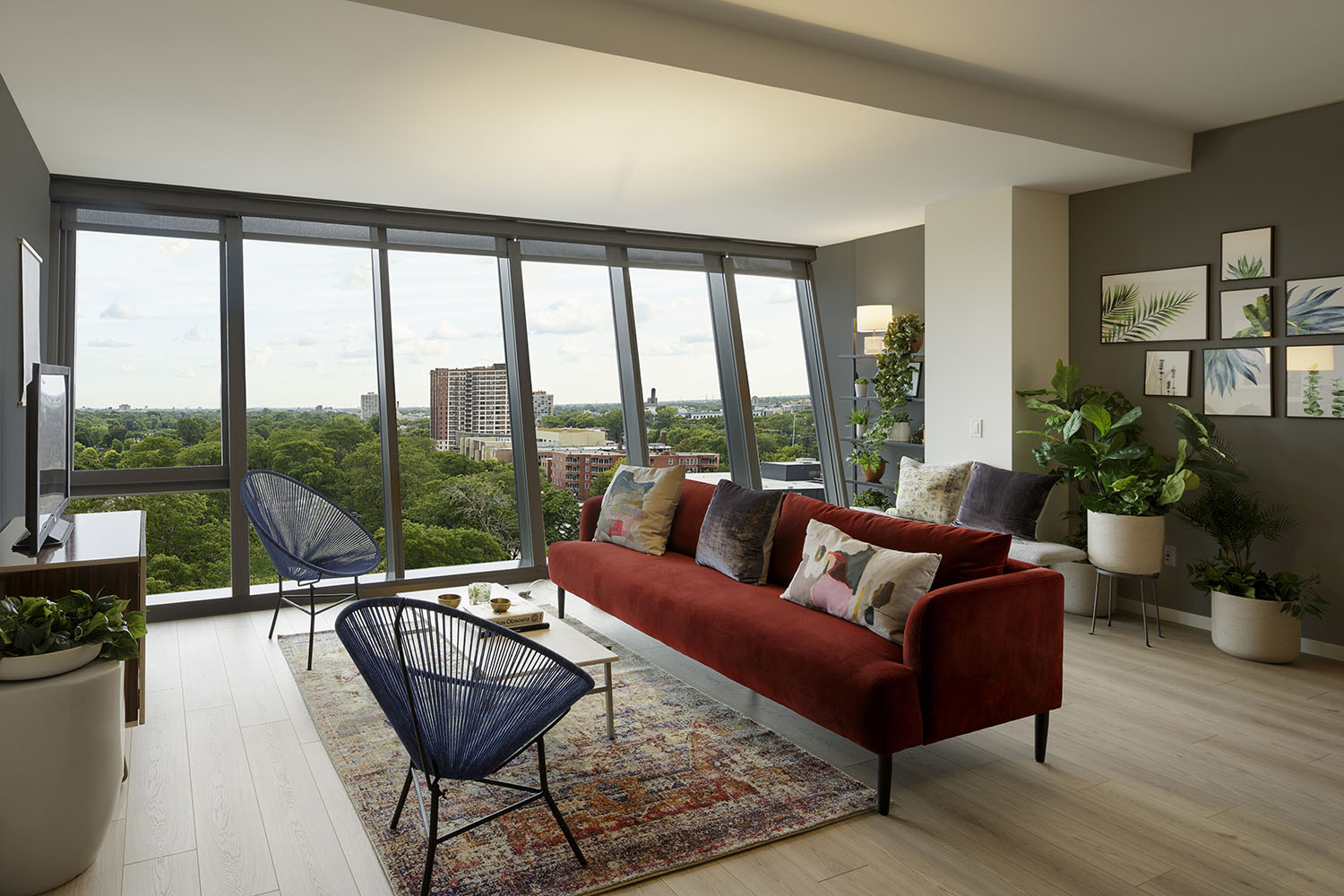 living room with red sofa and blue chairs with angled glass windows in background