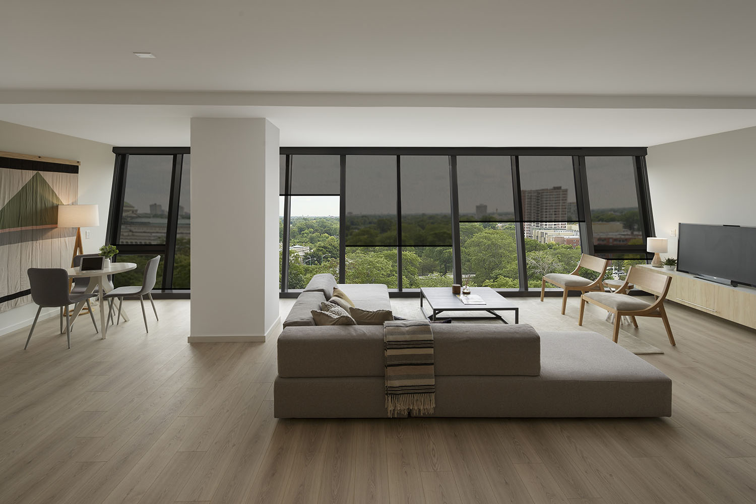 large open-plan living room with wood floors and angled glass windows in backhground