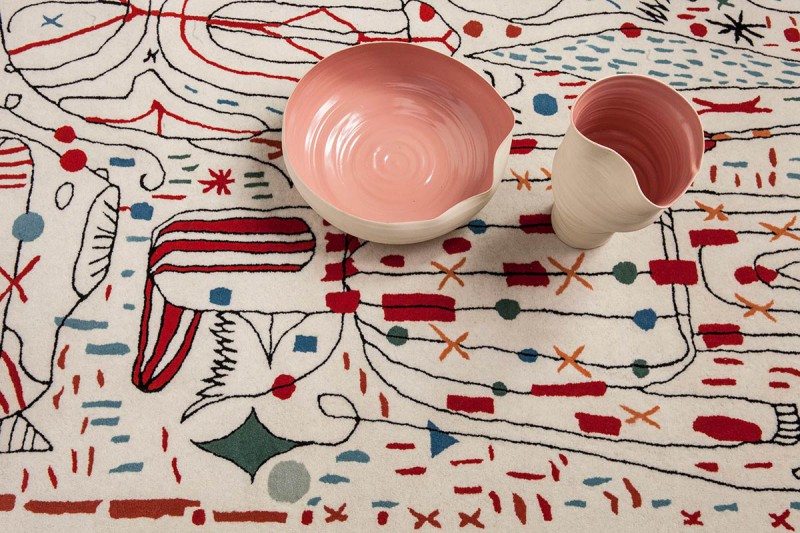two vases with pink insides sit on top of a wool area rug with colorful designs