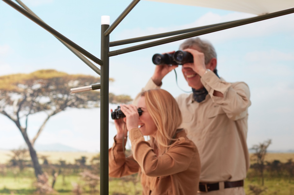 couple beneath minimalist parasol looking through binoculars