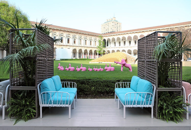 Komodo Modular Sofa blue cushions on white outdoor scene with marching pink rabbits and gorilla in background