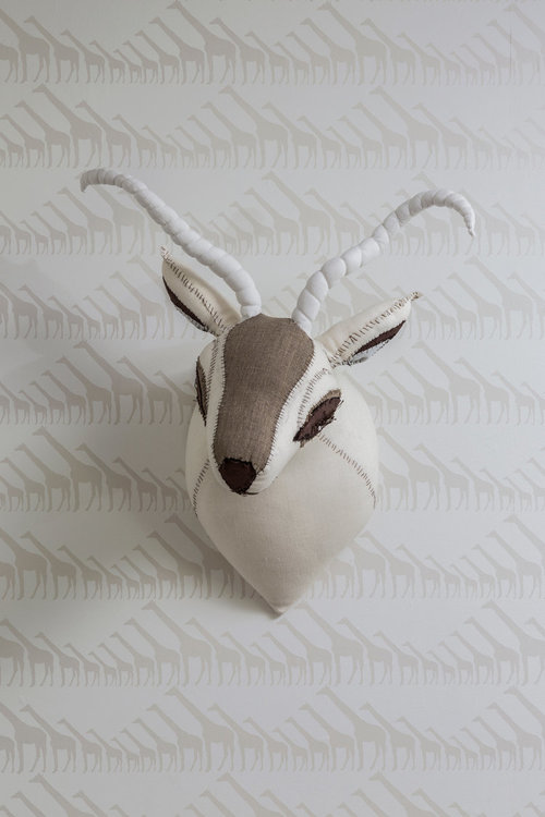 detail of beige giraffe wallpaper and stuffed animal head