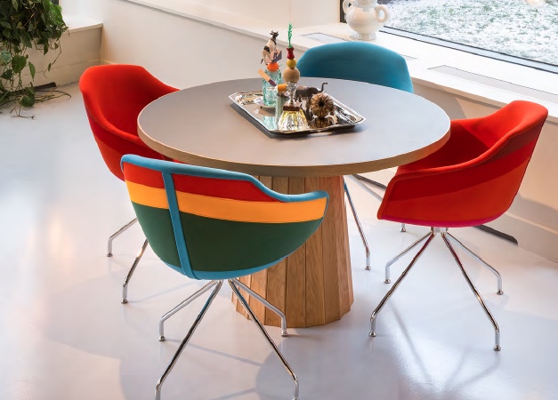 four bright upholstered dining chairs aroud a round table