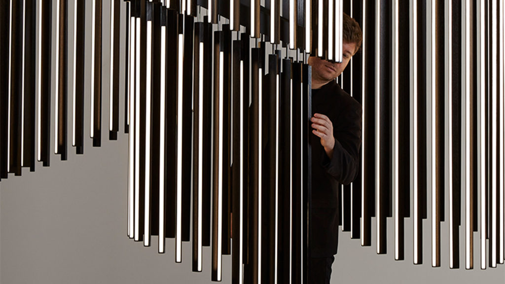 Stickbulb's Chime Chandelier four chandeliers in dark wood being adjusted with ball joint