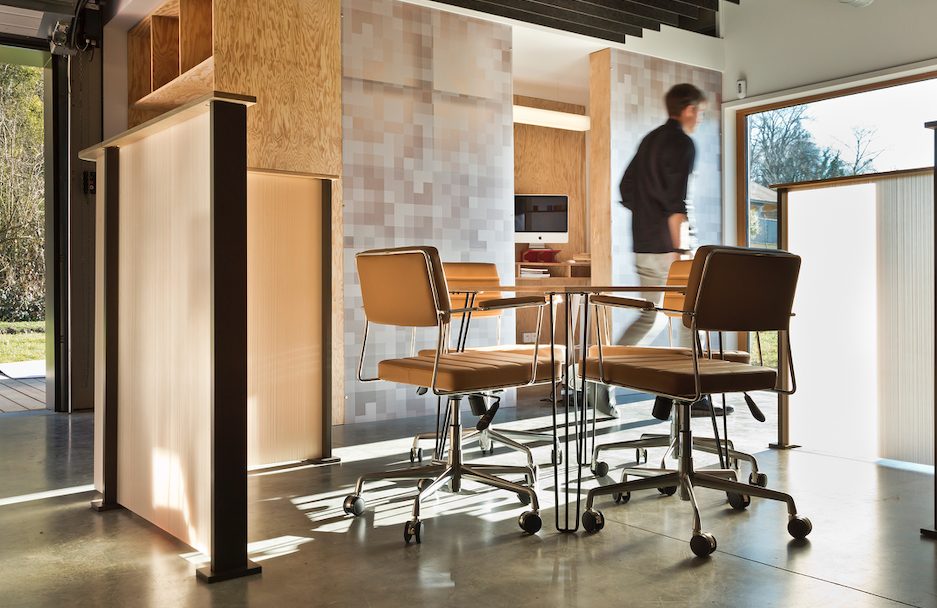 semi-private meeting space in open modern office with wood and resin half-wall partitions, table, and leather chairs