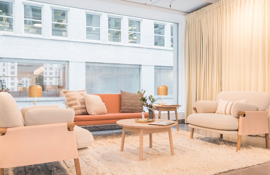 neutral sitting room with orange, peach, and beige upholstered furniture and large window
