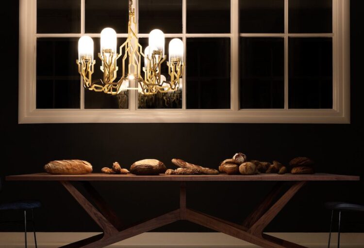 gold and glass geometric chandelier above wood table in dark modern dining room