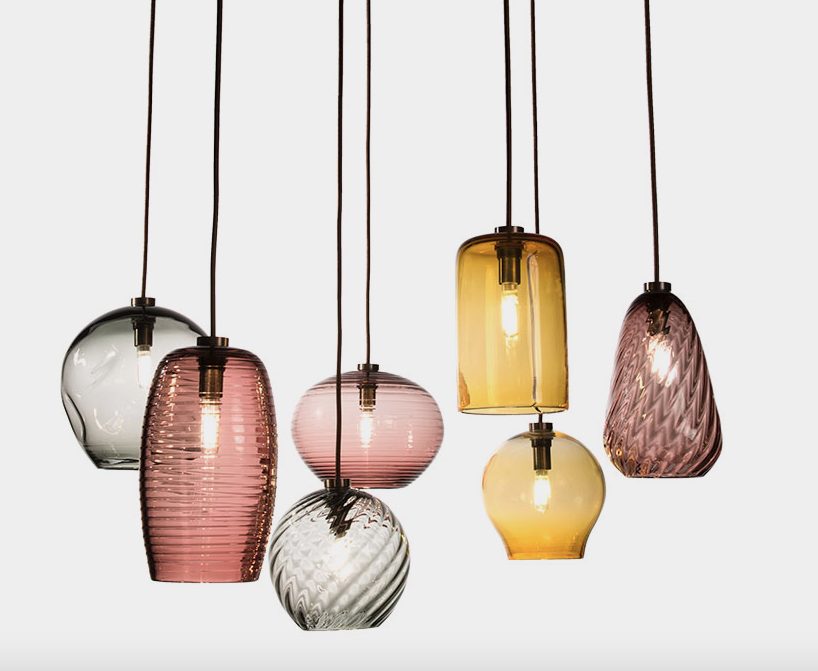 seven glass pendants hanging at different levels in amber, plum, and gray glass colors