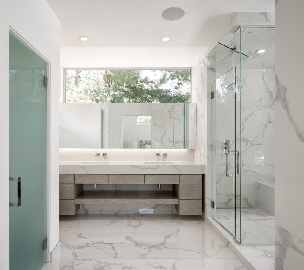 Fantini Mint Faucet in contemporary bathroom with glass shower and white solid surface countertops