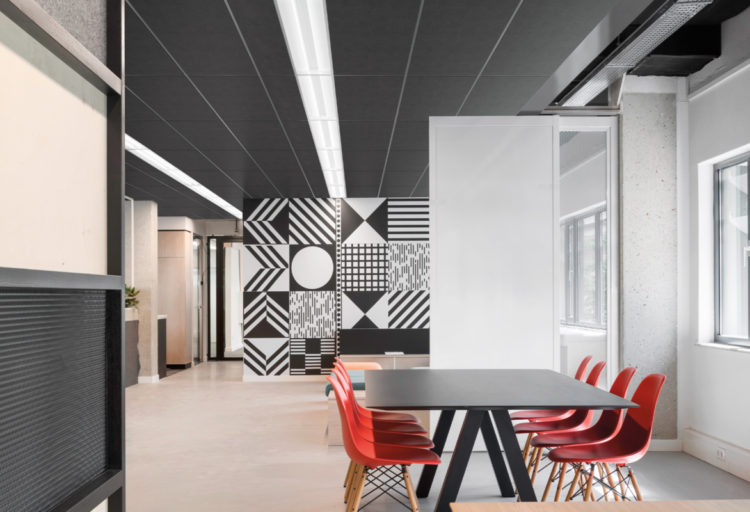 Fluxwerx LED Luminaire in office installed in black ceiling with conference table and red work chairs in foreground