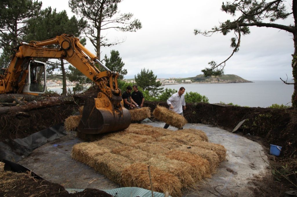 Truffle House during construction men moving hay bales with backhoe