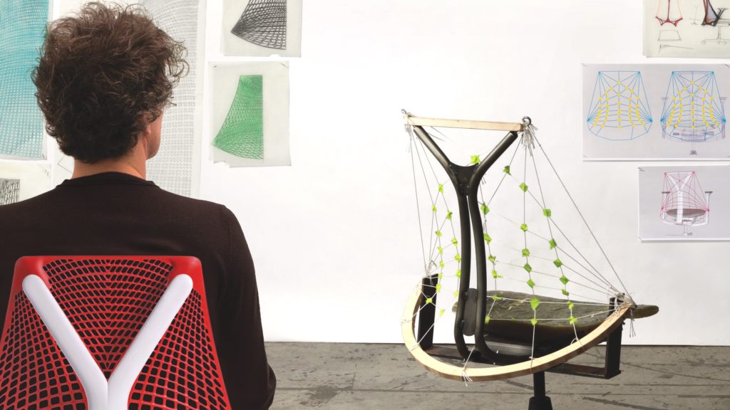 Yves Béhar Herman Miller Sayl Chair image of Béhar sitting in red Sayl across from an unfinished prototype of Sayl 