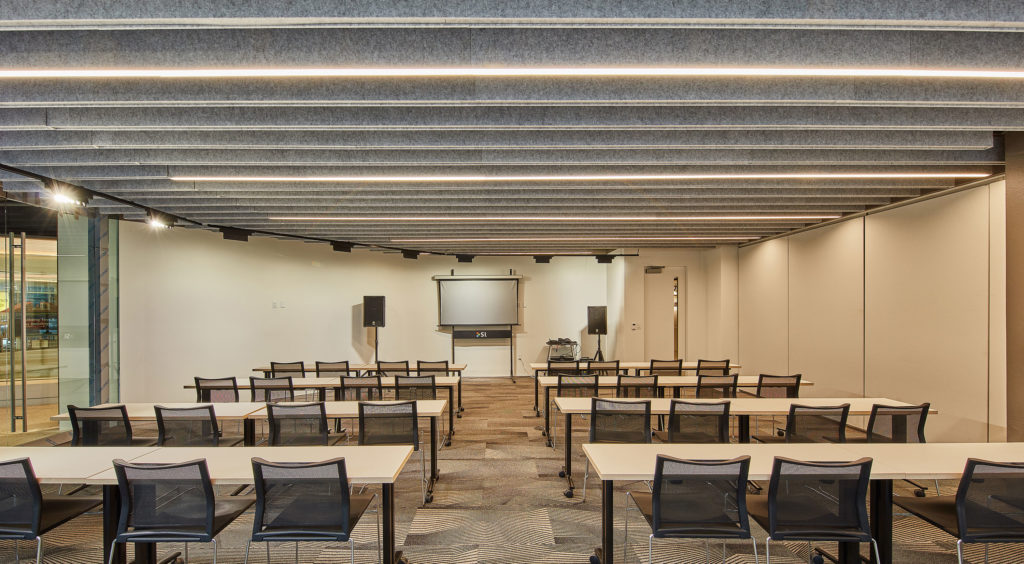 Focal Point Seem 1 Acoustic Luminaire presentation room view facing monitor with several tables and chairs