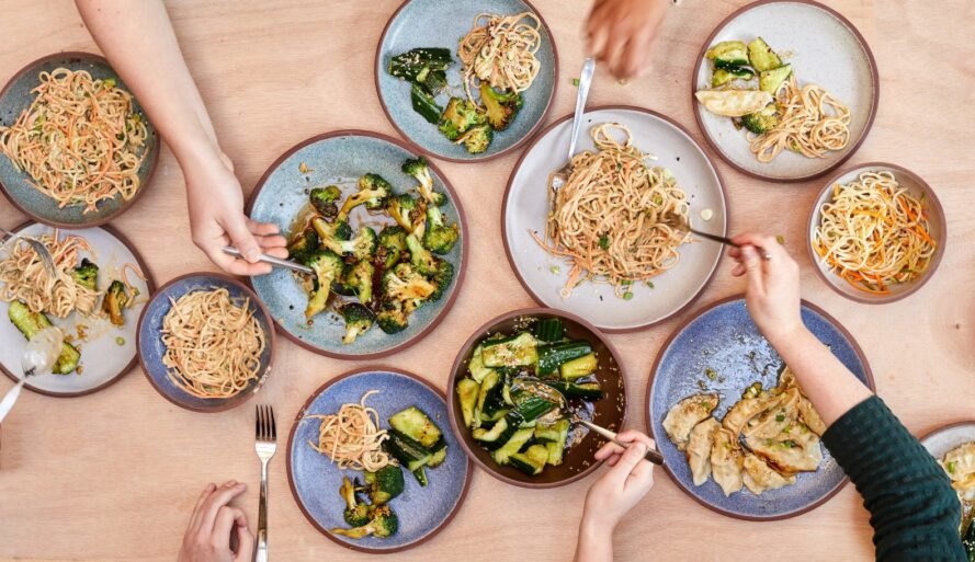 Granbyware assortment of plates and bowls filled with noodles and zucchini view from above