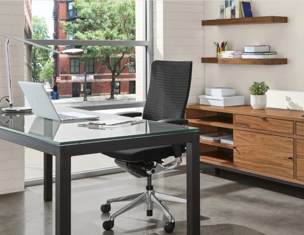 Room & Board Business Interiors Parsons Desk, Coral Office Chair, and Copenhagen Storage. Chair and Desk are black, credenza is natural wood in small office with view of storefront outdoors