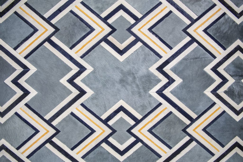 Kyle Bunting hide rugs Ipanema in gray, blue, and yellow intersecting triangles