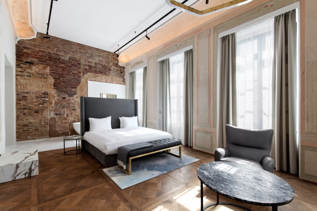 Hotel PACAI room interior with bed with black leather headboard and exposed brick wall