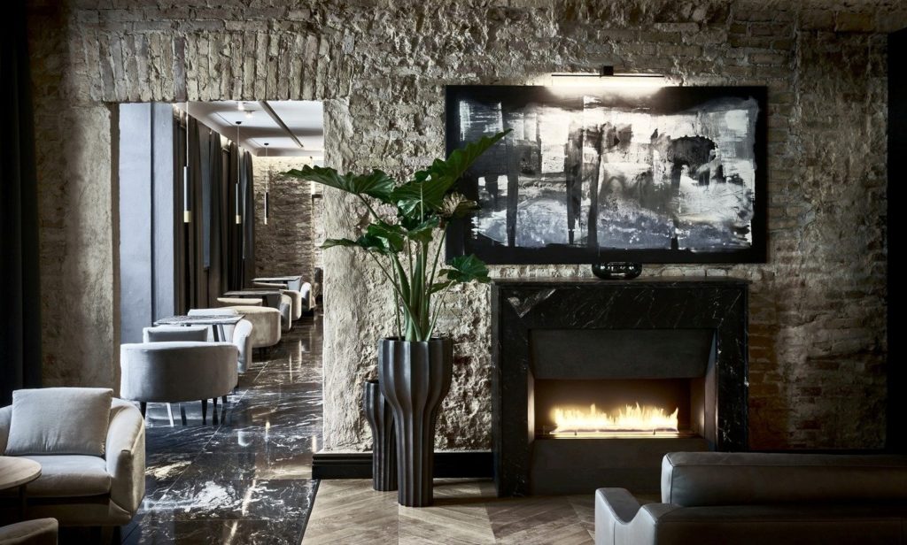Hotel PACAI interior lobby with original textured brick walls, gas fireplace and rows of cafe tables with plush chairs