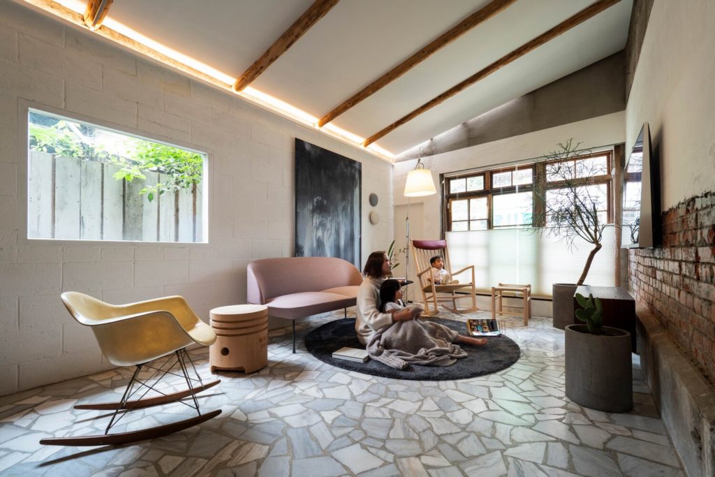Living Lab interior living room with mother and daughter watching tv; flagstone floor with stingray rocker and pink loveseat