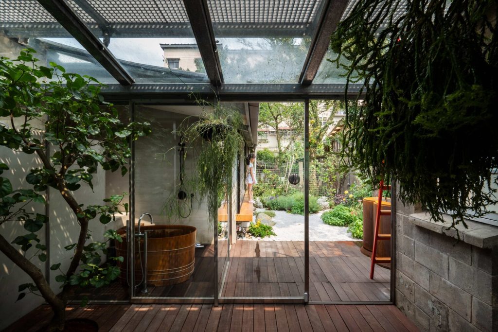 Living Lab view to outside through green room with many plants and vines and view of garden