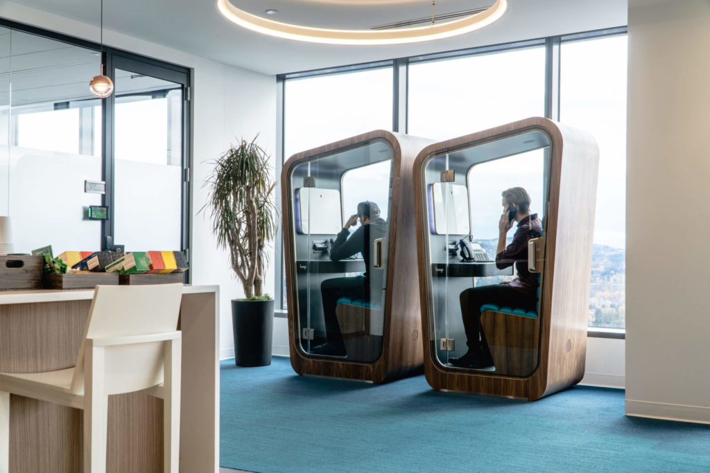 Loop Phone Booths two Solo models with wood grain exterior and men inside on phone in office space