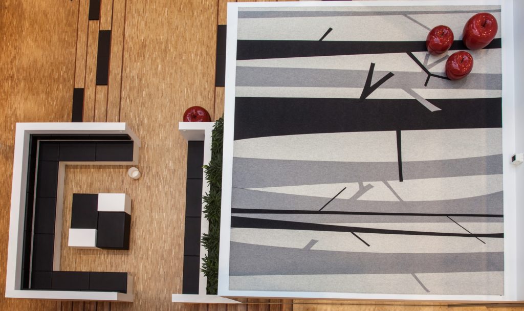 Fraster Felt Rug Collection custom rug in white, gray, and black with pattern of winter trees on small balcony overlooking open office seating
