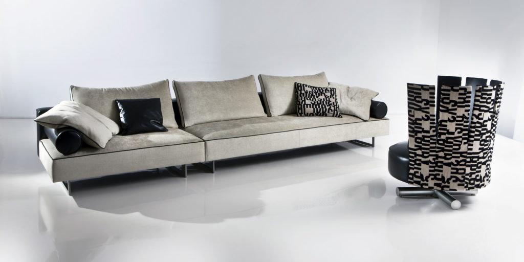 Nube Velvet Sofas Aline sofa in grey with patterned pillows opposite chair