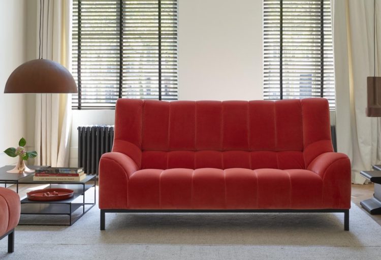 Ligne Roset Phileas Sofa medium-sized sofa in salmon with ottoman off to the side shown in home living room near fireplace with white walls and gray rug