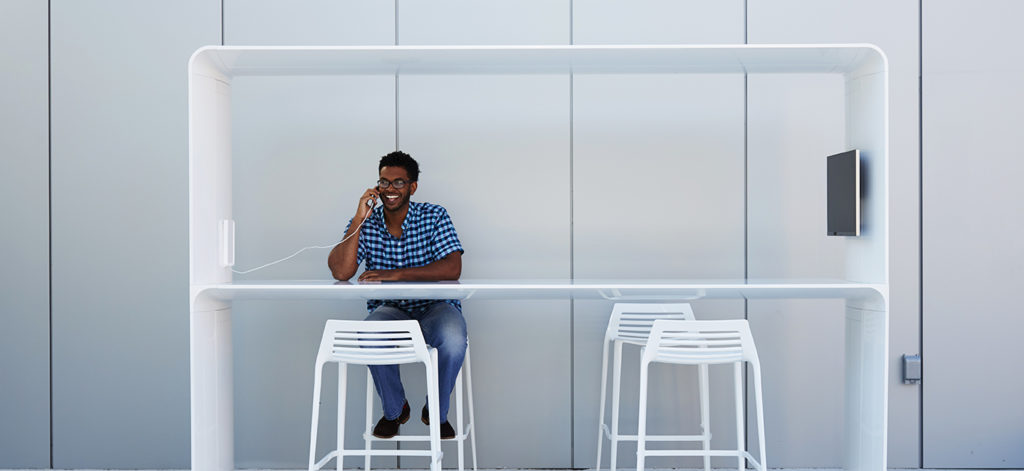 Landscape Forms' Go Outdoor Table white standing height with canopy and man speaking on phone