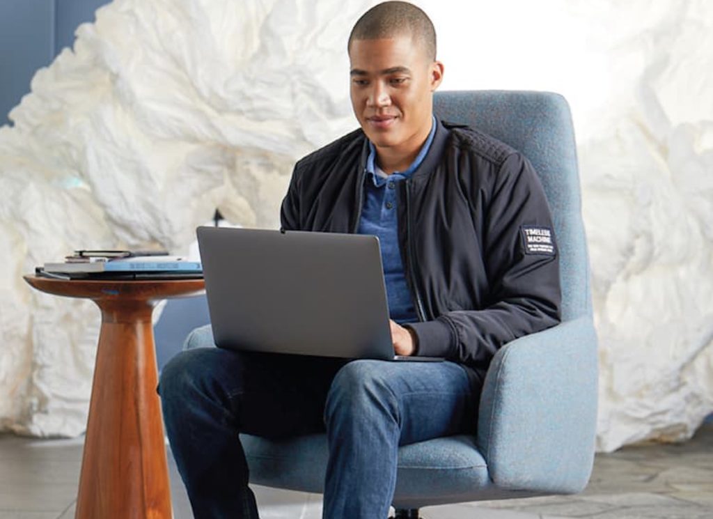 SitOnIt Envoi Lounge highback blue with man seated on it working on laptop next to small table