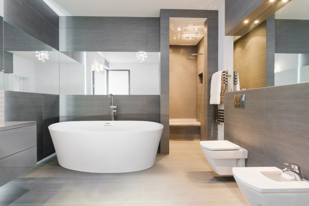 Orleans by Americh front view in nice bathroom with gray tile, mirror above tub, and gray vanity