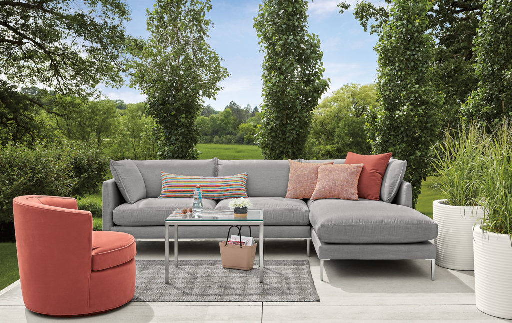 Room & Board Seating Ambrose swivel chair in salmon on outdoor patio with gray modular sofa