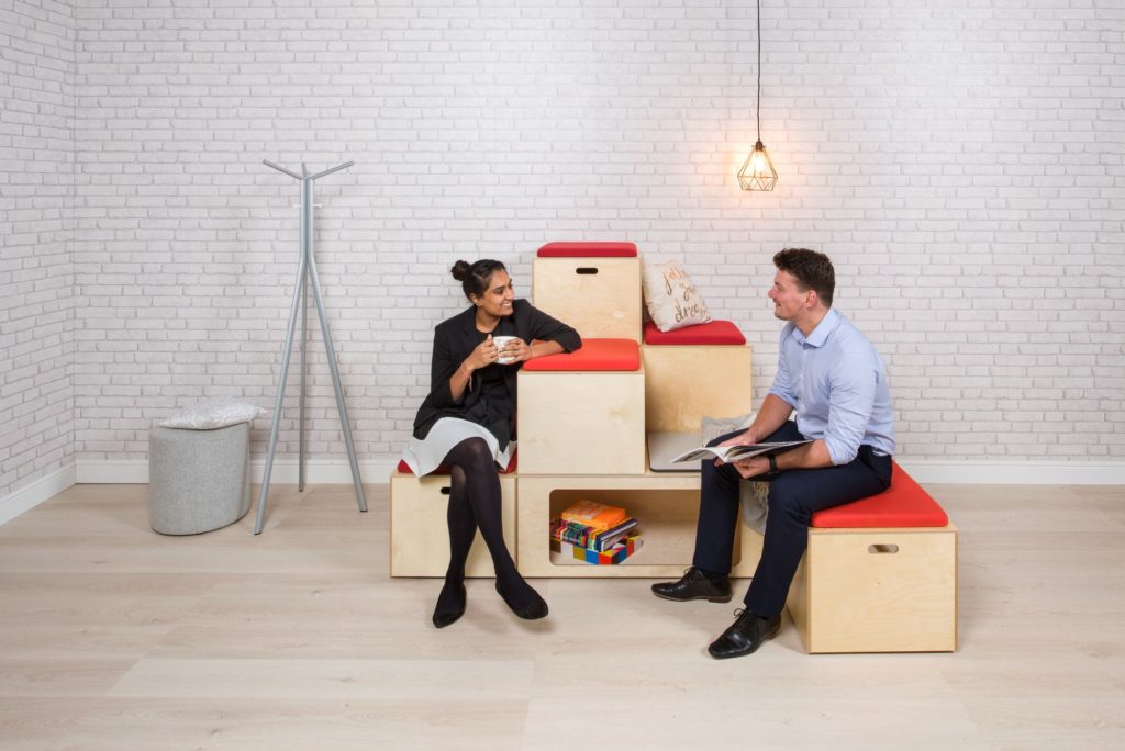 Spacestor Bleachers modular seating with light wood laminate and orange seat pads with a man and woman talking 