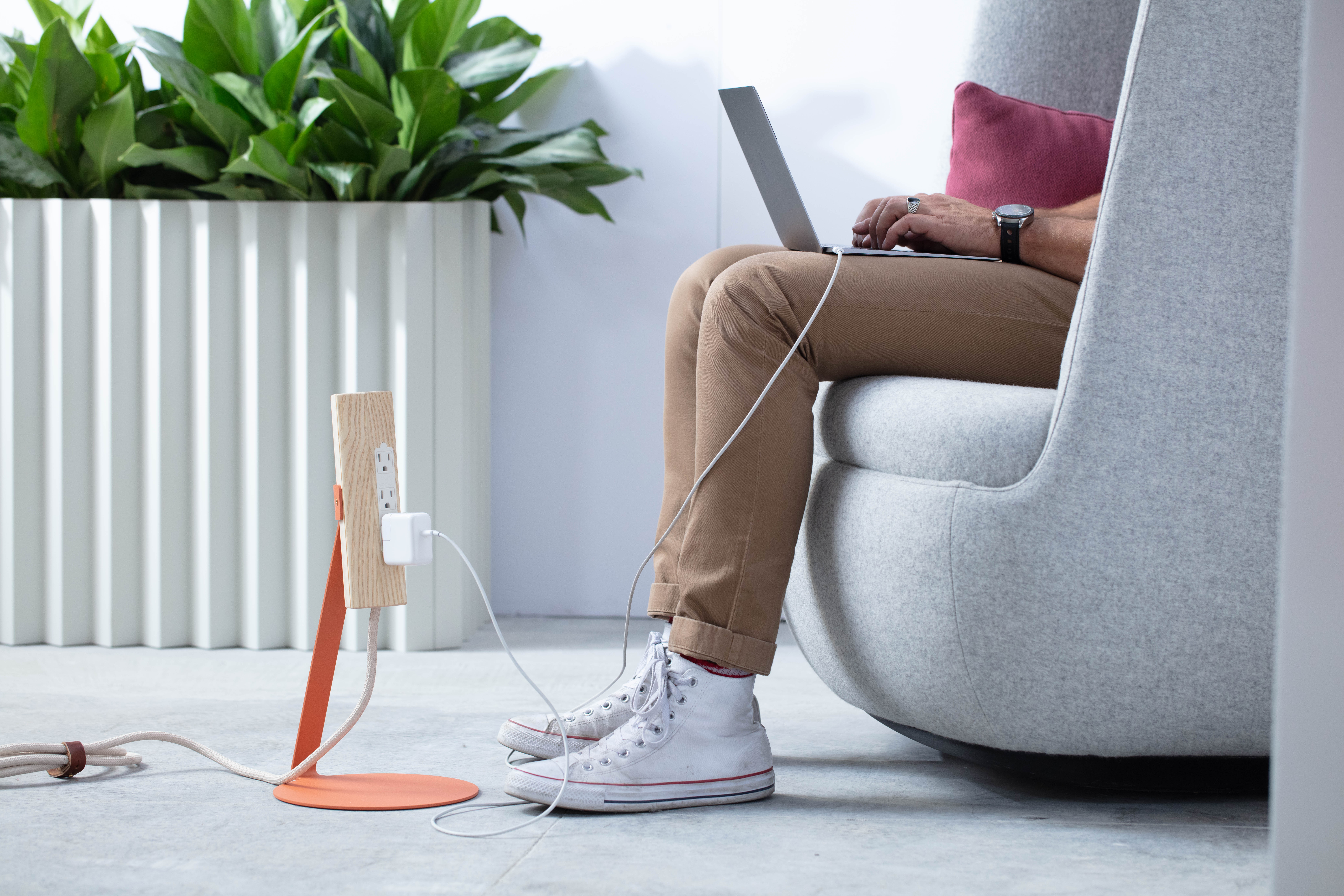 Most Modest's Niko free-standing power orange next to legs of person sitting in chair