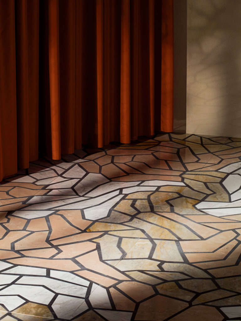 Del Savio 1910 Marble Vague collection on floor with red curtains behind