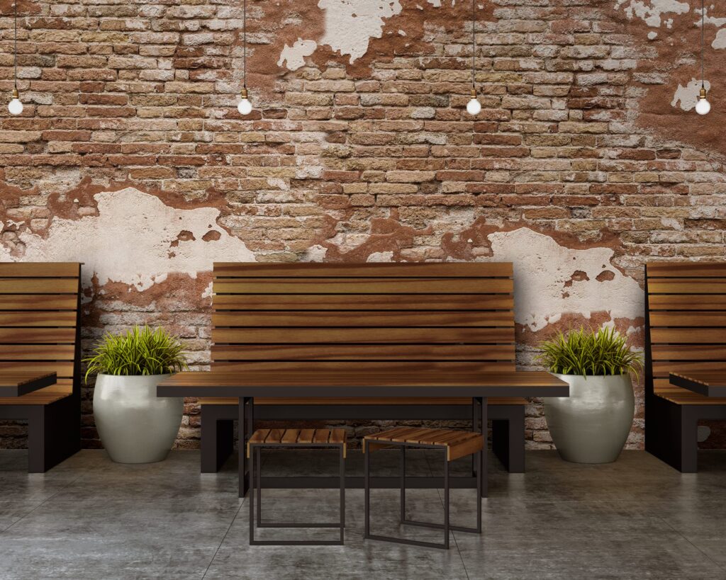 Garda Collection bench, table, and stools in front of brick wall