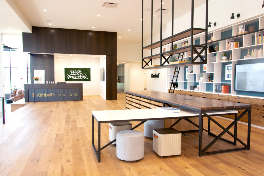 custom tables and bookcases wiht Kimball Ottomans in design hub where Kimball was just awarded the WELL Health and Safety seal