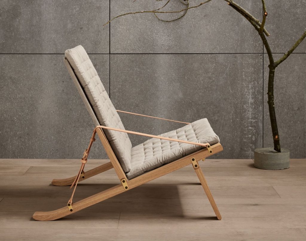 Plico Chair side view in room with small sculpture of a tree