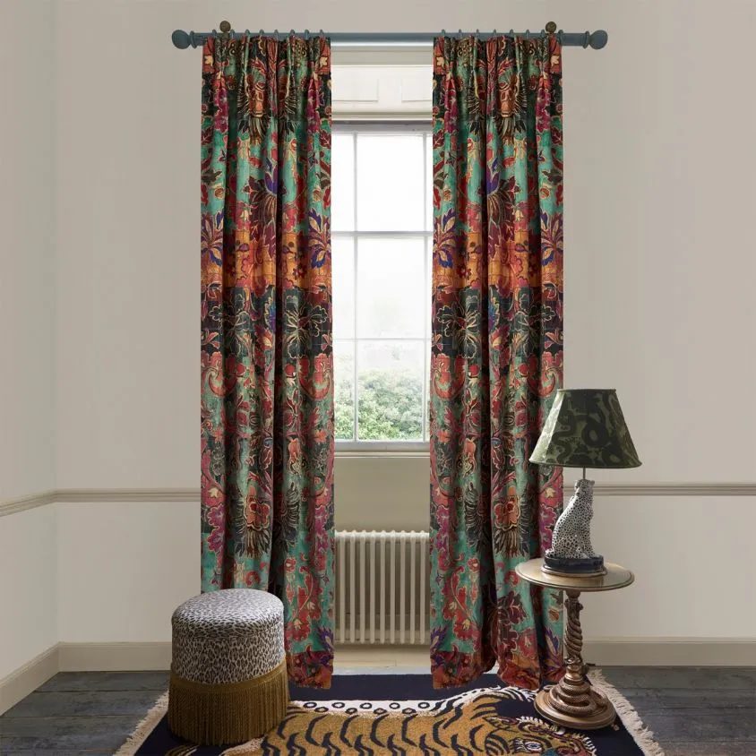 Andastra textile detail pattern with different floral forms on a grid background in bright colors like purple, teal, orange, and red on curtains against white walls with leopard lamp and leopard ottoman in the foreground