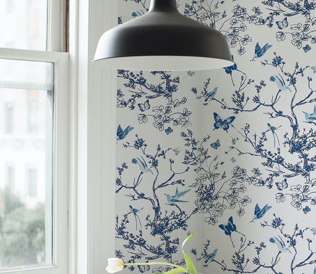 Schumacher Flight of Fancy wallpaper with birds, butterflies, and tree branches with pendant light near window