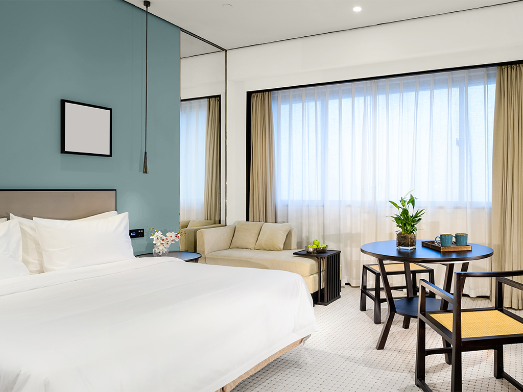 MODE ephemera moody blue on hotel room wall behind bed with table and settee