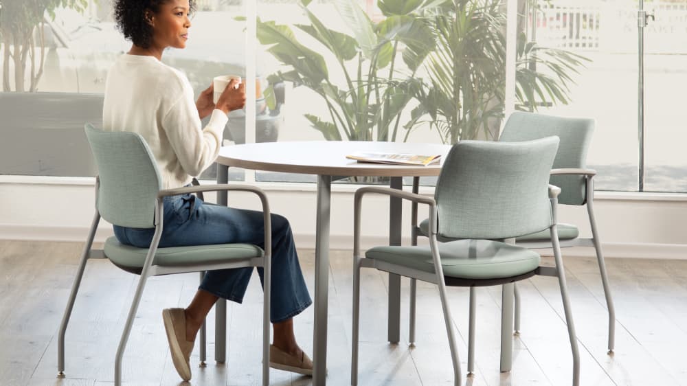 Cora side chair three chairs around table with mint upholstery and woman drinking coffee
