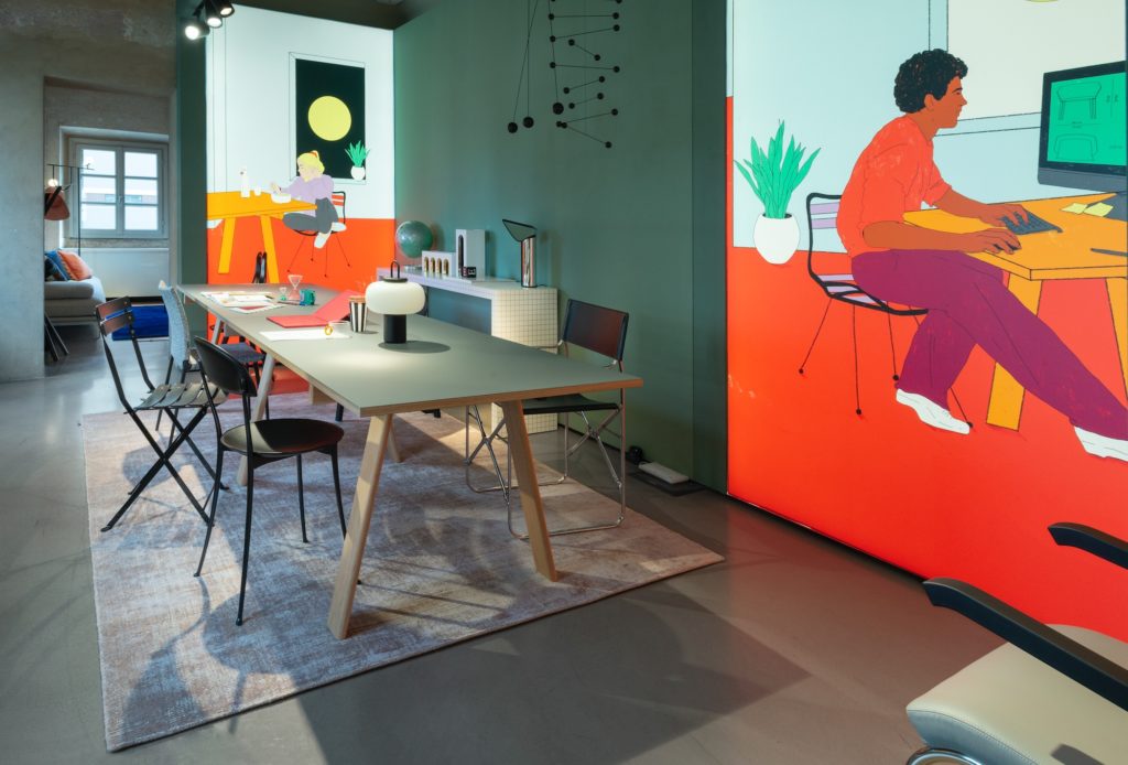 Intimacy Collection with Ambrosiano table, and Dan Chairs and large colorful mural of a man working on a computer