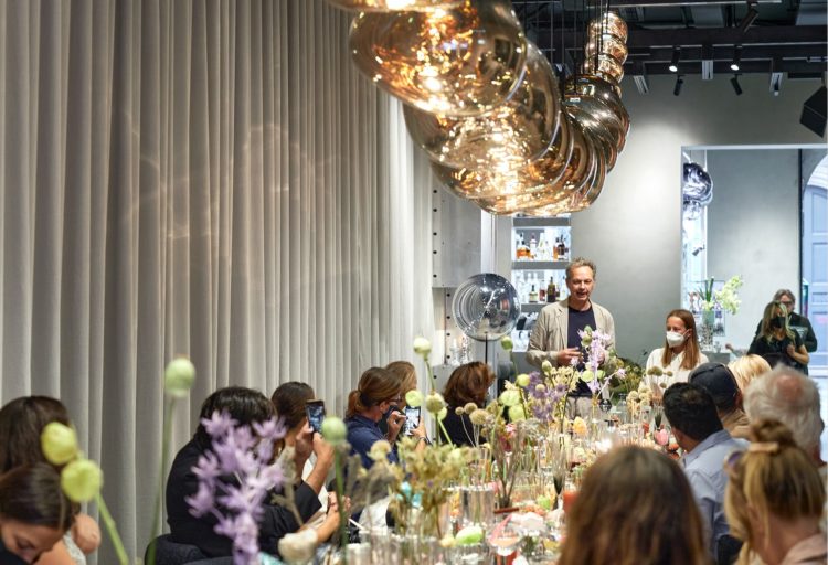 Tom Dixon in Milan Melt chandelier above table with fancy food and people