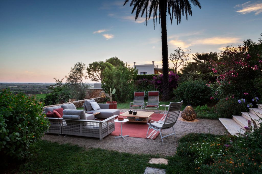 Boundless Living Solaria collection with red carpet and gray chairs/sofas surrounded by lush foliage