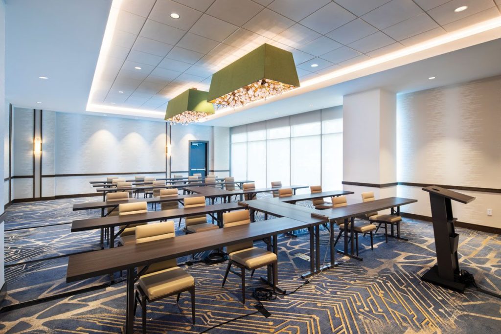 H.E. Williams Lighting trapezoidal luminaire with small bulbs and green shade in meeting room