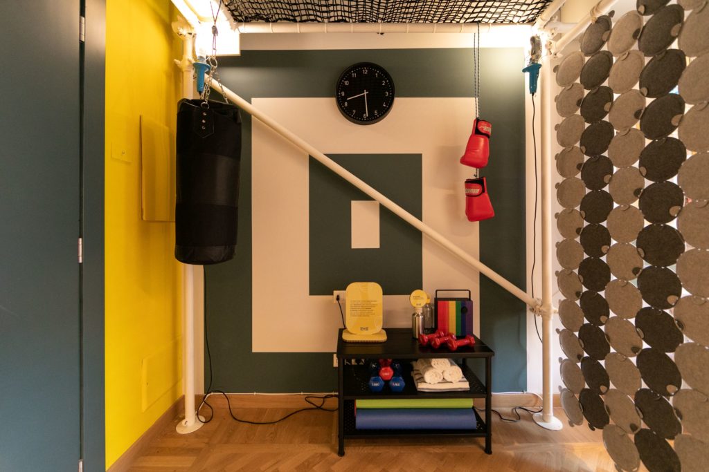 future modes of living exhibit small room privacy screen, low table, boxing heavy bag, and clock