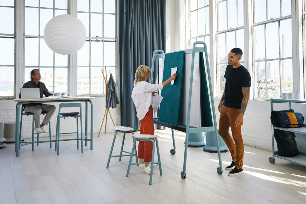 Teknion Routes high desk, high stools, white board, and three people working in sunny office